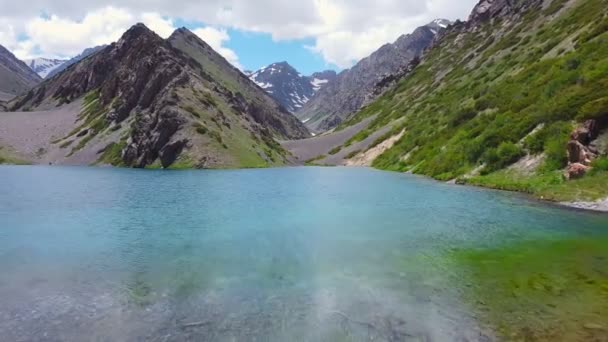 A drone flies over a turquoise mountain lake - Footage, Video
