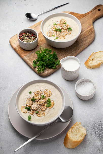 Bowl with mushroom cream soup, parsley, salt and croutons, toast on grey table. Champignon soup. - Zdjęcie, obraz