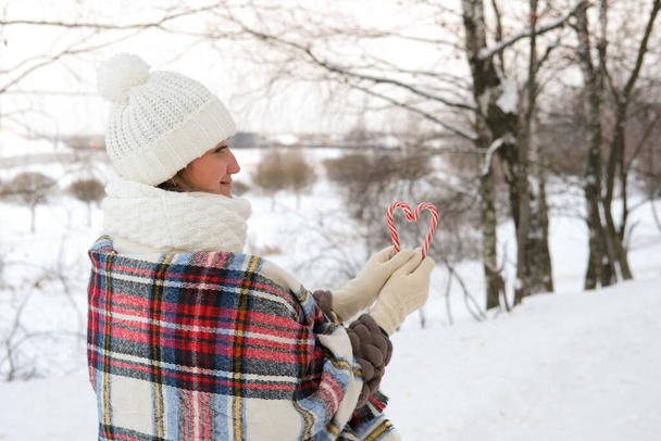 A woman walks through the winter forest, she holds candy canes in her hands - Foto, Imagen