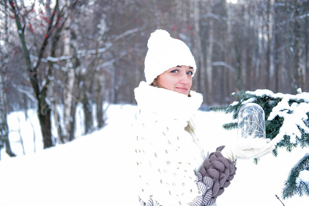 Portrait of a beautiful girl in a winter park, in her hands she holds a lantern with light bulbs - Photo, image