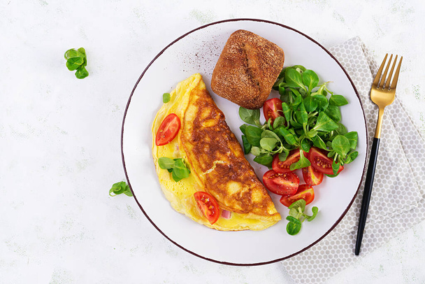 Omeleta s rajčaty, šunkou, sýrem a kukuřičným salátem na talíři. Frittata - italská omeleta. Pohled shora, režie - Fotografie, Obrázek