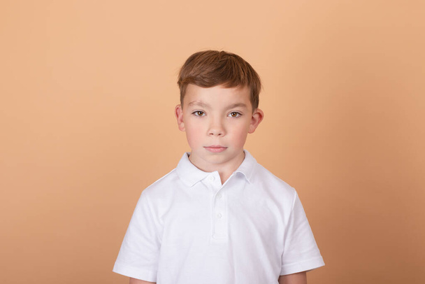 Portrait of school boy with facial expression isolated over light brown background. Concept of feelings, youth, fashion, facial expression, emotions, lifestyle, ad - Photo, Image