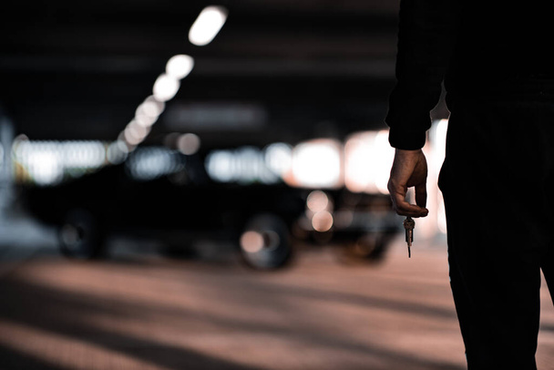 Un primer plano de un hombre sosteniendo las llaves del coche sobre un fondo borroso - Foto, Imagen