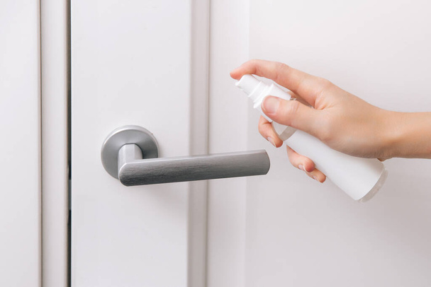 Cleaning white door handles with an antiseptic wet wipe and sanitizer spray. Disinfection in hospital and public spaces against corona virus. Woman hand using towel for cleaning home room door link - Fotografie, Obrázek
