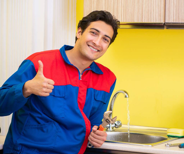 Tesisatçı mutfakta musluğu tamir ediyor. - Fotoğraf, Görsel