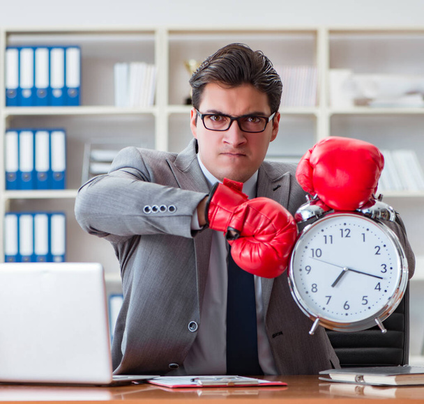 Mérges üzletember bokszkesztyűvel az időgazdálkodás koncepciójában - Fotó, kép