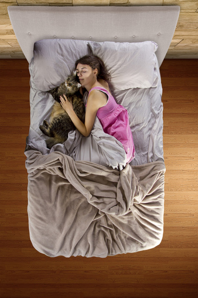 Young teenager sleeping with a pet cat - Fotó, kép