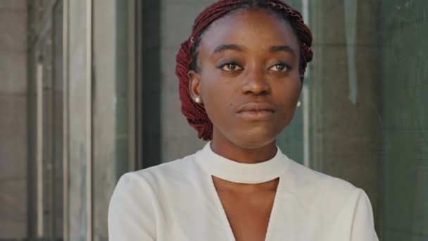 Close-up retrato feminino Africano americano menina senhora afro mulher estudante empresário rosto elegante modelo fica na cidade no fundo do edifício olhando para a distância pensando sonhando sonhos de planejamento - Filmagem, Vídeo