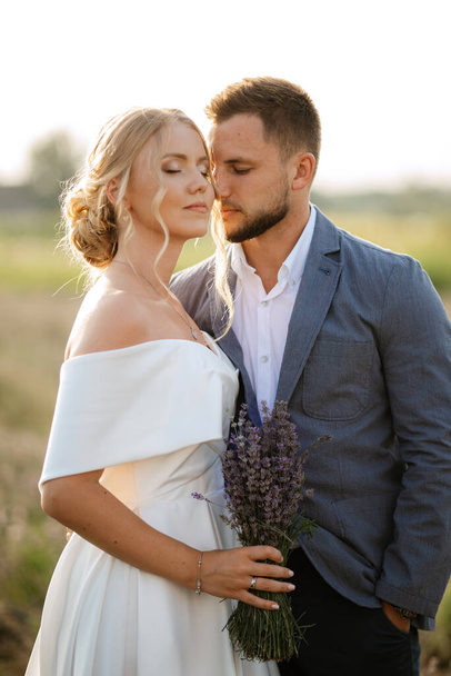 bride and groom on a walk in the lavender field - Foto, afbeelding