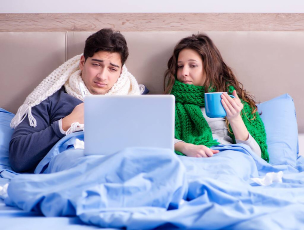 Zieke vrouw en echtgenoot in bed met laptop - Foto, afbeelding