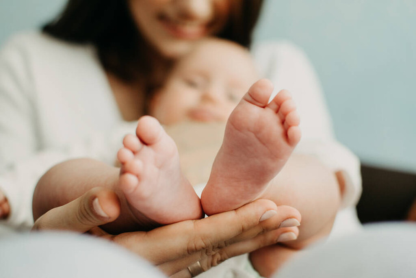 Yeni doğan bebekler için sağlık sigortası. Yeni Bebek İçin Hayat Sigortası. Anne yeni doğmuş bebeğin ellerini tutuyor. Bebek ayakları ebeveynin ellerinde - Fotoğraf, Görsel