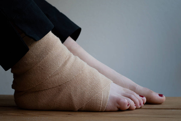 El primer plano de los pies de una persona. Un pie envuelto con vendaje elástico debido a una lesión. - Foto, imagen