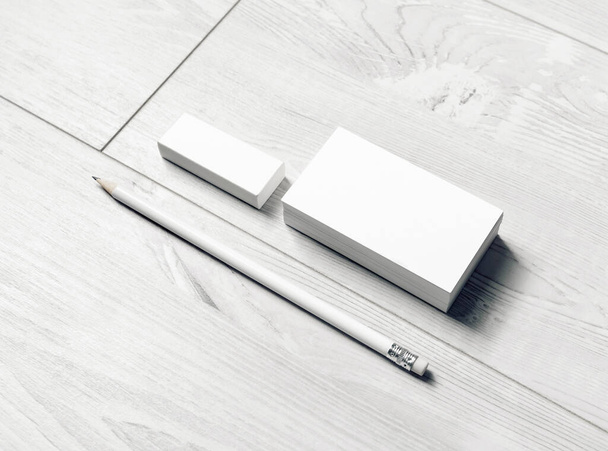 Λευκά χαρτικά. Λευκές επαγγελματικές κάρτες, μολύβι και γόμα σε ανοιχτό ξύλινο φόντο. - Φωτογραφία, εικόνα