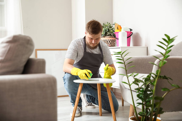 Young man with sponge cleaning table at home - Photo, Image