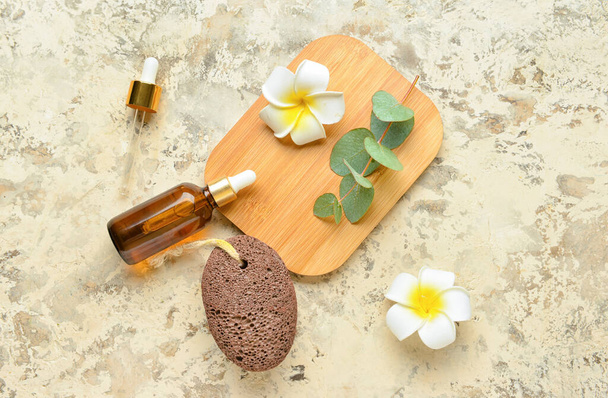 Composición con piedra pómez para masaje de pies, botellas de aceite esencial y flores sobre fondo grunge - Foto, Imagen