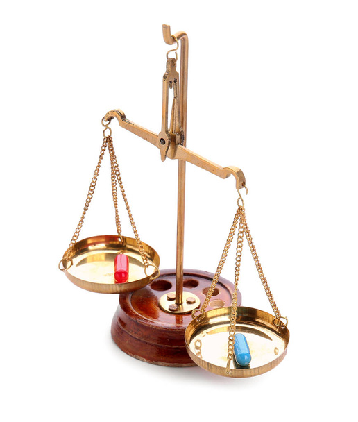 Blue and red pills on scales of justice against white background. Concept of choice - Zdjęcie, obraz