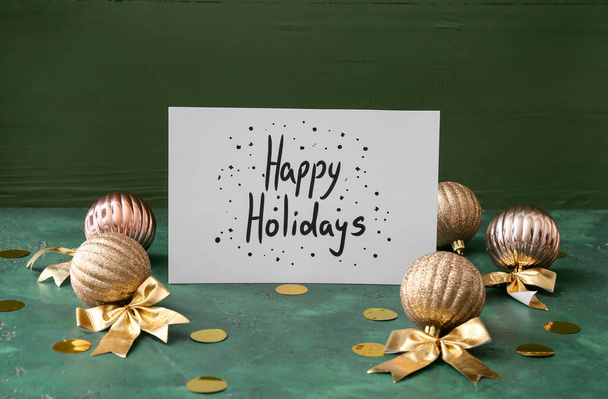 Text HAPPY HOLIDAYS and Christmas decor on green background - Фото, зображення