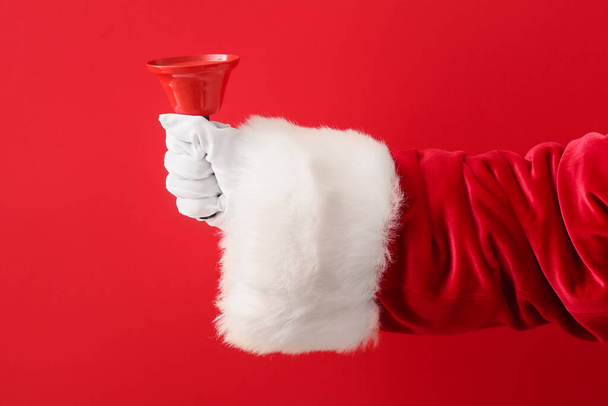 Santa mano con campana di Natale su sfondo rosso - Foto, immagini