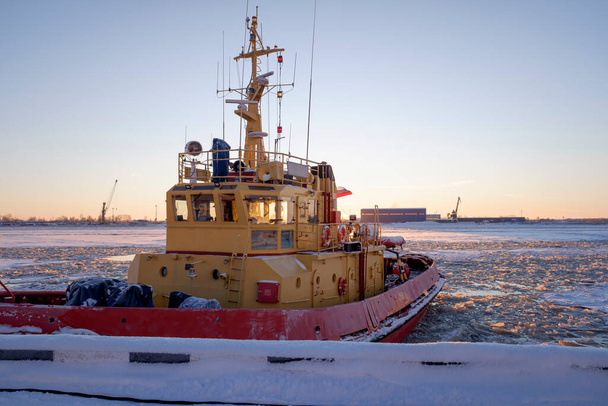 de sleepboot aangemeerd op de pier op een ijzige zonnige winterdag aan de Severnaya Dvina rivier in Archangelsk - Foto, afbeelding