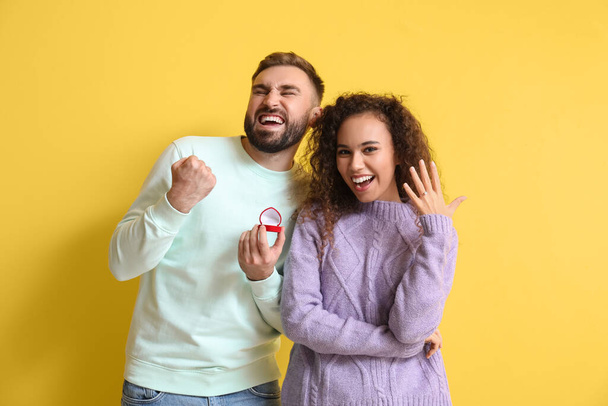 Glücklich verlobtes junges Paar nach Heiratsantrag auf farbigem Hintergrund - Foto, Bild