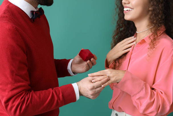 Giovane uomo proponendo alla sua ragazza su sfondo di colore - Foto, immagini