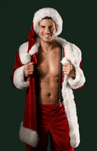 Sexy young man in Santa costume on dark background - Фото, изображение