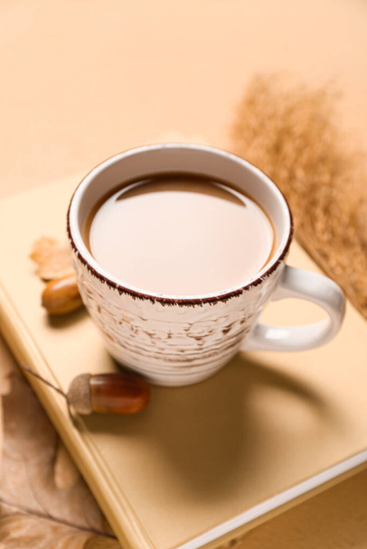 Tasse de café savoureux, livre et décor d'automne sur fond beige - Photo, image