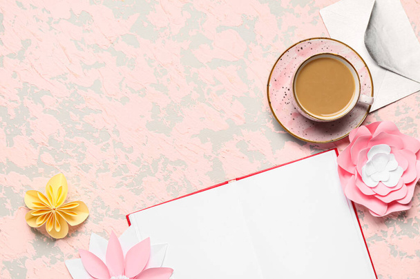 Чашка вкусного кофе, пустая книга и бумажные цветы на бежевом фоне - Фото, изображение