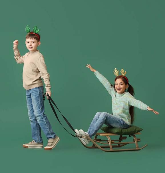 Funny little children with sledge on color background - Фото, изображение