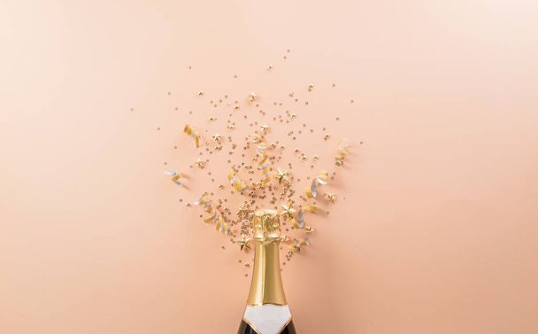 Šťastný Nový rok oslavy pozadí koncepce. Láhev šampaňského se zlatými vánoční míč a hvězda na pastelovém pozadí. - Fotografie, Obrázek