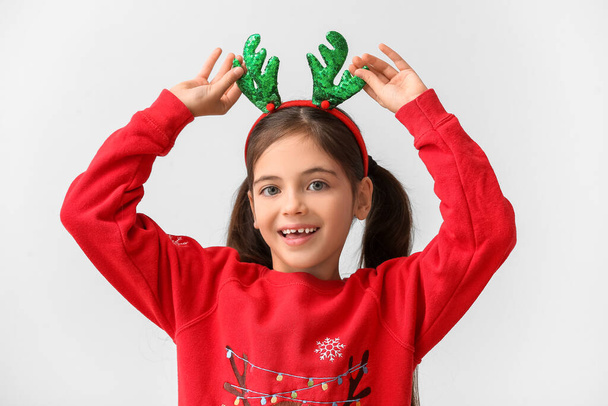 Grappig klein meisje met rendieren hoorns op lichte achtergrond - Foto, afbeelding