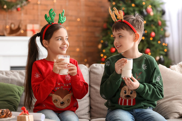 Glückliche kleine Kinder, die an Heiligabend zu Hause Milch trinken - Foto, Bild