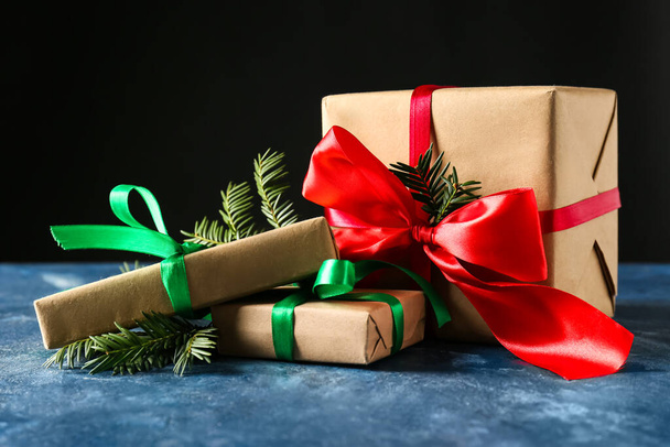 Стильні різдвяні подарункові коробки та ялинкові гілки на столі на темному фоні
 - Фото, зображення