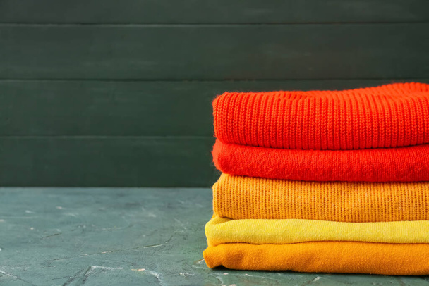 Stack of different cozy sweaters on grunge background - Photo, Image