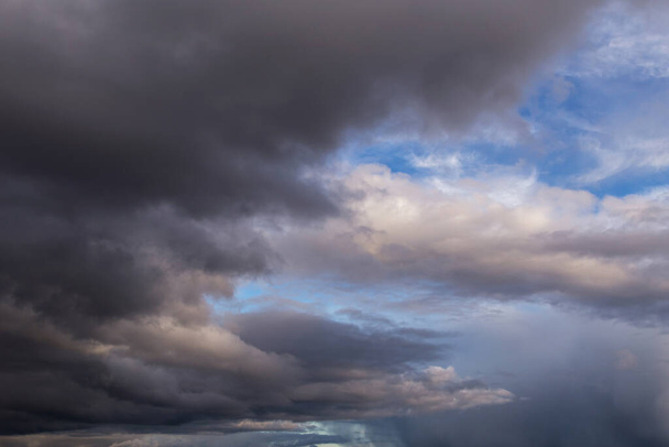 Epic Dramatic storm dark grey cumulus rain clouds against blue sky background texture, thunderstorm. Darkness and light - Fotó, kép