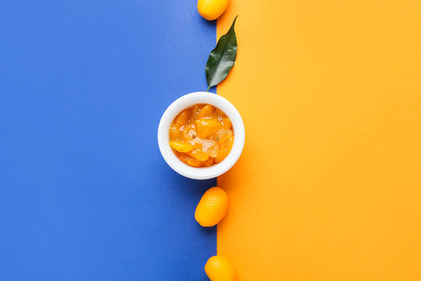 Bowl of tasty kumquat jam and fresh fruits on color background - Фото, изображение