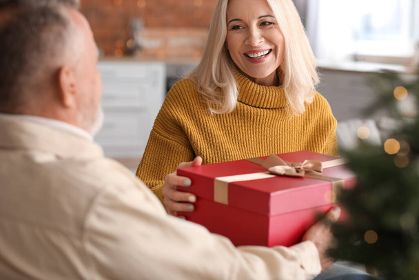 Happy mature couple with gift at home on Christmas eve - Фото, зображення