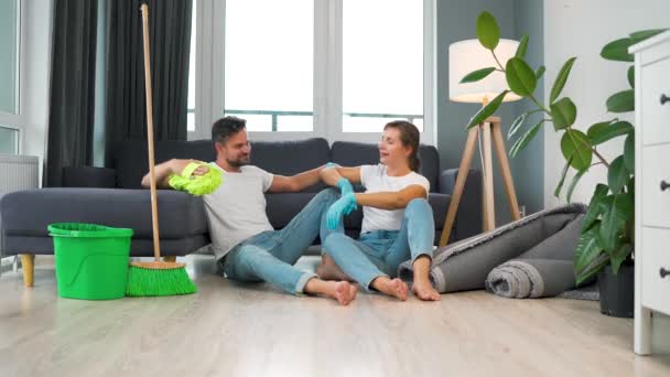 La coppia stanca si siede sul pavimento in una stanza e si dà cinque a vicenda dopo aver finito di pulire la casa. Rallentatore - Filmati, video