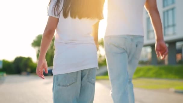 Dad and daughter walk around their area at sunset. Child holds fathers hand. Back view. Slow motion - Footage, Video