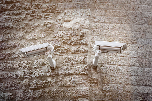 two  observation cameras on a ancient natural stone wall - Photo, Image