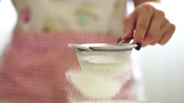 Mujer tamiza lentamente la harina a través de un pequeño tamiz de metal - Imágenes, Vídeo