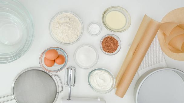 Ingrediënten, borden, perkament papier close-up op keukentafel, uitzicht van boven. Stap voor stap chocoladetaart recept - Foto, afbeelding