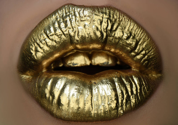 Golden lipstick on lips, female gold mouth. Imprint lips. Luxury cosmetics for women. Golden lip texture. - Valokuva, kuva
