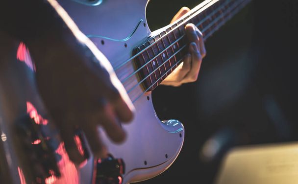 Close-up of a man playing the bass guitar. - Foto, afbeelding