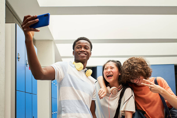 Groupe multi-ethnique d'étudiants prenant un selfie au collège. - Photo, image