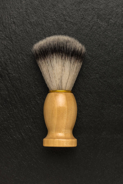 Stylish shaving brush with a wooden handle on a stone background. Men's accessories for appearance care. Flat lay. - Fotó, kép