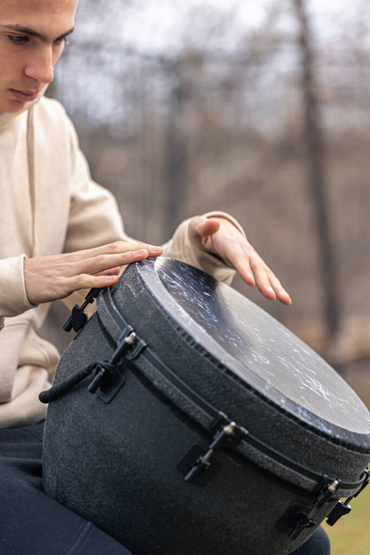 A man plays the djembe drum outside. - Photo, Image