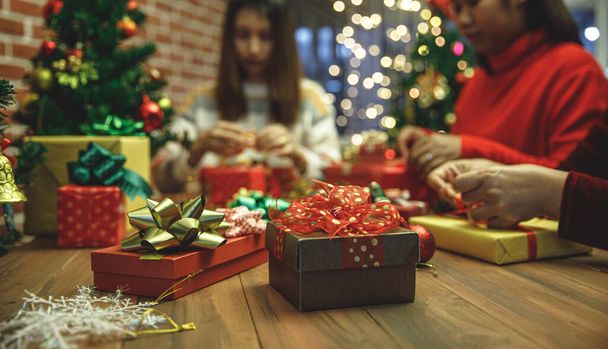 Belle boîte cadeau sur une table en bois décorée par un arc coloré et charmant. Les gens l'emballent comme cadeau de Noël pour une fête de famille fascinante pendant les vacances d'hiver. Ajouter du bruit pour s'adapter à l'image de style vintage. - Photo, image