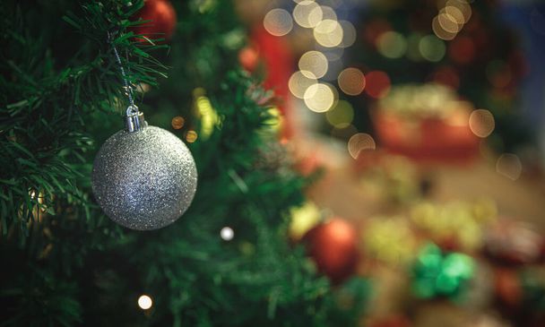 La palla vivida d'argento sveglia pende su albero di Natale tradizionale come bella decorazione di ornamento per festa di casa meravigliosa di celebrazione di anno nuovo durante notte invernale. Aggiungi un po 'di rumore per adattarsi all'immagine in stile vintage - Foto, immagini