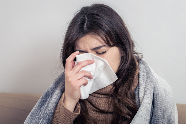 Eine kranke junge Frau zu Hause auf dem Sofa mit einer Erkältung. - Foto, Bild
